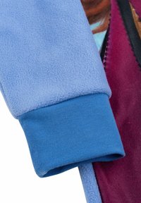 Maniche in tessuto felpato blu con finitura testurizzata e una morbida foderatura interna. Presenta un polsino blu a contrasto e un accento color bordeaux intenso.