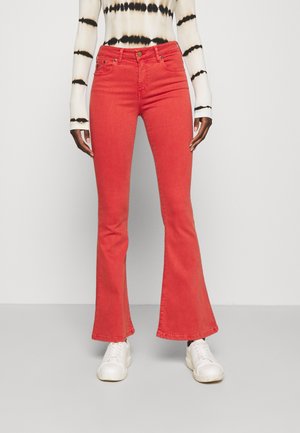 Los jeans de mezclilla rojos acampanados presentan una cintura de altura media, un diseño clásico de cinco bolsillos y están elaborados con una textura suave. Combinados con zapatillas blancas.