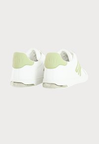 White sneakers with a smooth texture, green accents on the heel and side, silver detailing on the sole, featuring embossed branding.