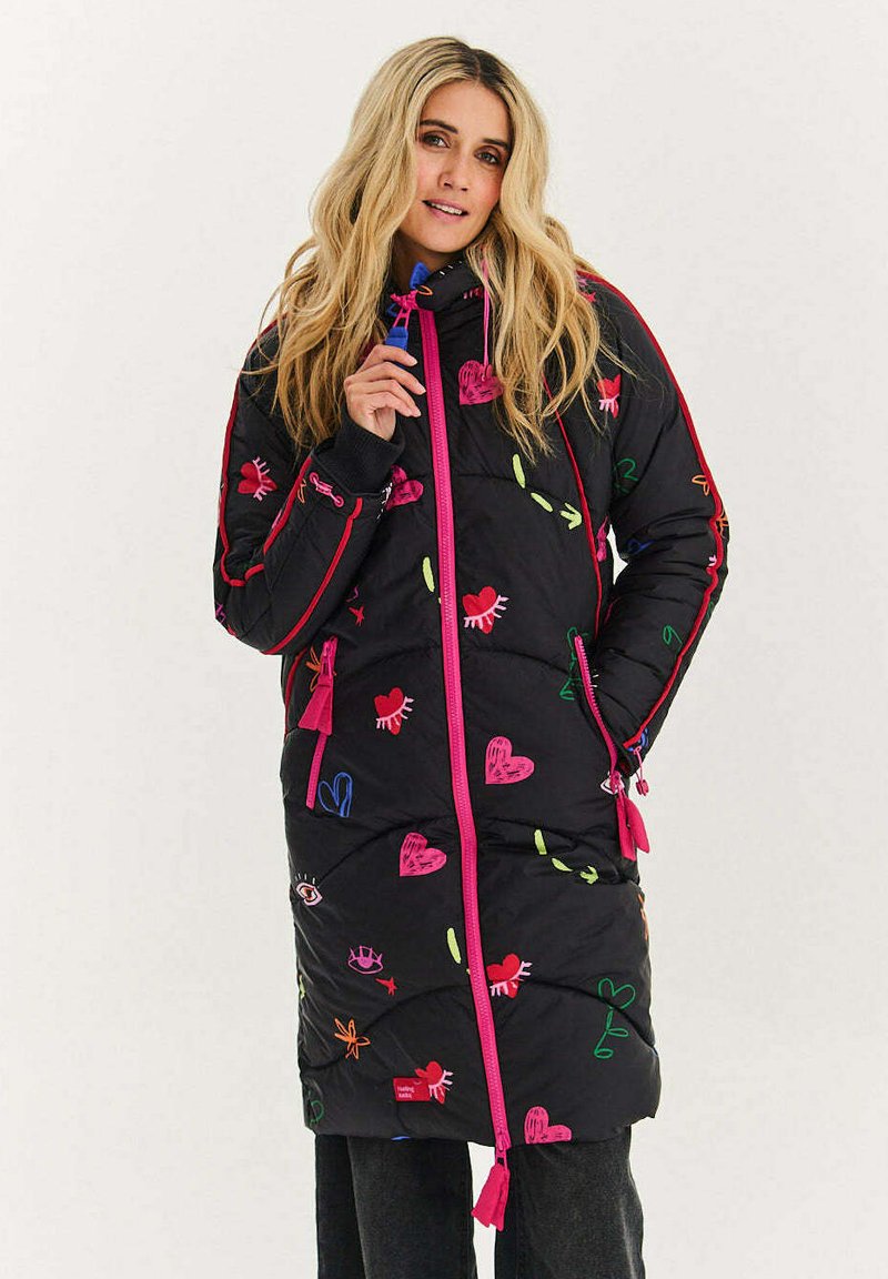 Dlouhý černý péřový kabát s barevnými vyšívanými vzory, růžovými detaily a kontrastními zipy. Má kapuci a boční kapsy.