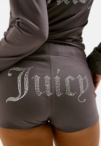 Gray shorts made of smooth fabric featuring "Juicy" in rhinestones, positioned on the back with a curved font and sparkling accents.