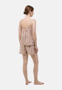 Ensemble de pyjama en coton à rayures comprenant un haut ample à bretelles ajustables et un short avec des bords froncés. Les couleurs incluent beige, rouge et pêche.