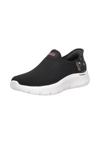 Zapatos slip-on negros con parte superior de malla transpirable, suela blanca y acentos con estampado floral en el talón. Diseño ligero y flexible.
