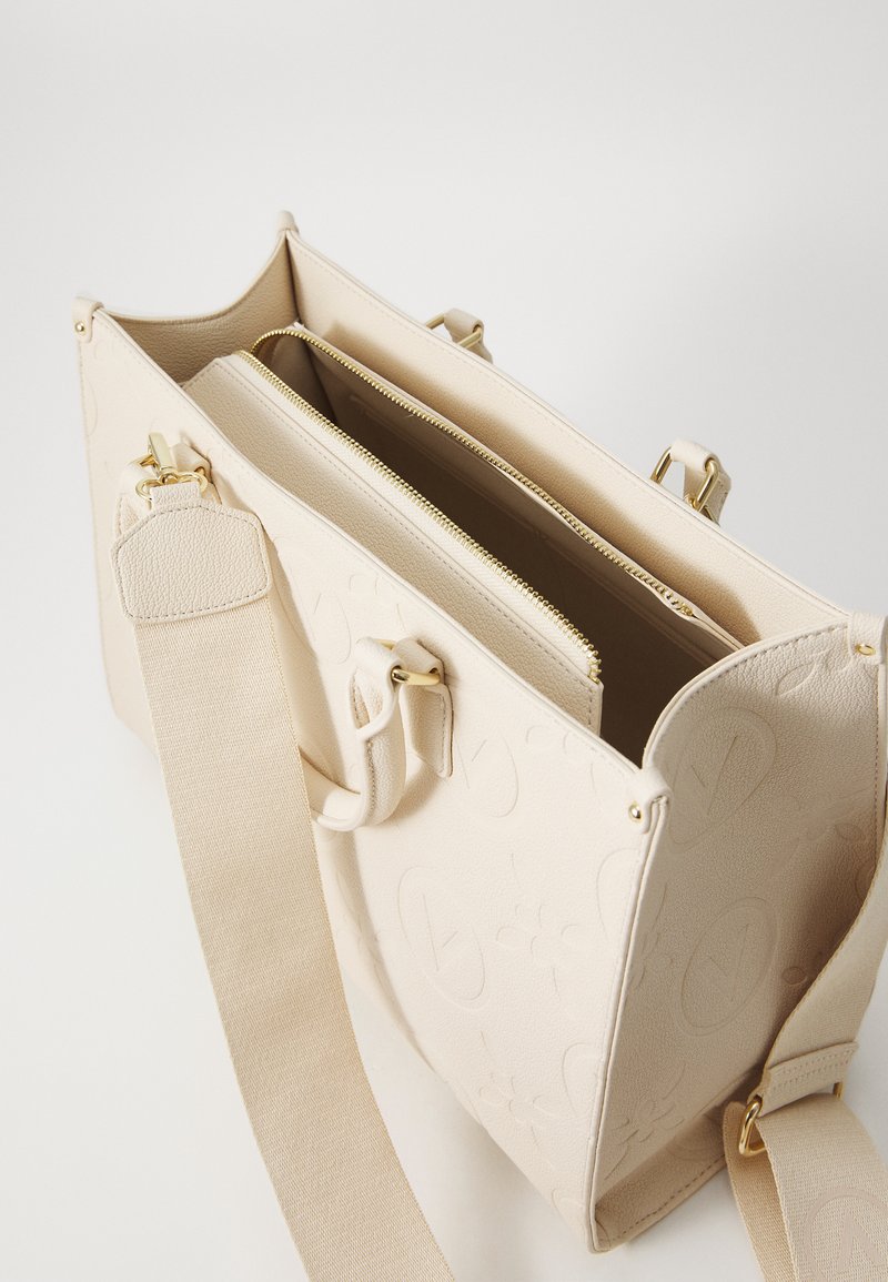 Sac en cuir beige avec motif de logo en relief, compartiments à double zip, accessoires en métal doré et large bandoulière en tissu.