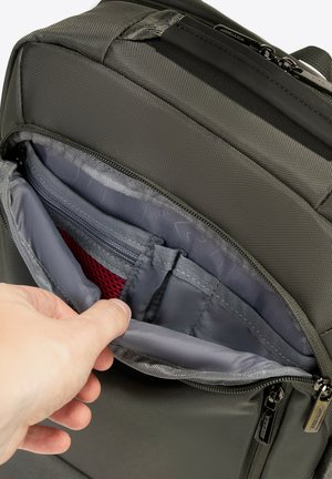 Szary plecak z tkaniny z otwartą kieszenią zapinaną na zamek, ukazującą siatkową przegrodę i miejsca do organizacji w jaśniejszym szarym wnętrzu.