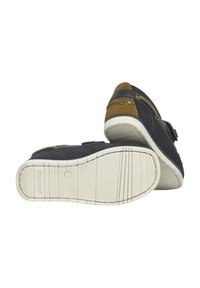 Zapatos de tela azul con acentos de ante marrón, suela de goma plana, característica de correa ajustable y patrón de textura en la parte inferior.