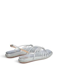 Sandal in argento con design a più cinghie, finitura metallica liscia, cinturino alla caviglia regolabile e dettaglio della suola intrecciata texture.