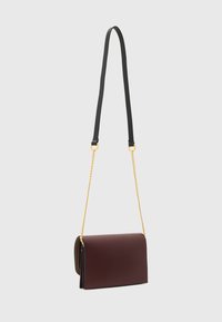 Bordeaux læder håndtaske med fold-over design, der har en sort justerbar rem og en gylden kæde accent. Glat tekstur, minimalistisk stil.
