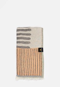Coperta in tessuto con motivi a strisce grigio chiaro, arancione e nero; bordo frangiato; texture morbida; etichettata con un tag nero.