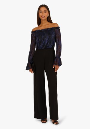 Top navy con motivo, off-the-shoulder con scollo arricciato e maniche a sbuffo, abbinato a pantaloni neri a gamba larga con vita alta.