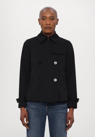 Veste noire croisée avec col, ornée de boutons brillants, d'un design court et de poignets ajustables. Tissu lisse et texturé.