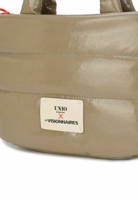 Beigefarbene glänzende Tasche mit horizontalem Steppmuster und orangem Akzent. Mit einem Etikett mit der Aufschrift "UNIO HAMBURG X LES VISIONNAIRES". Glatte Textur.