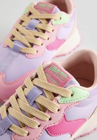 Wielokolorowe sneakersy z miękkiego lawendowego materiału, różowymi skórzanymi akcentami i zielonymi plastikowymi detalami. Grube beżowe sznurowadła z neonowymi akcentami.