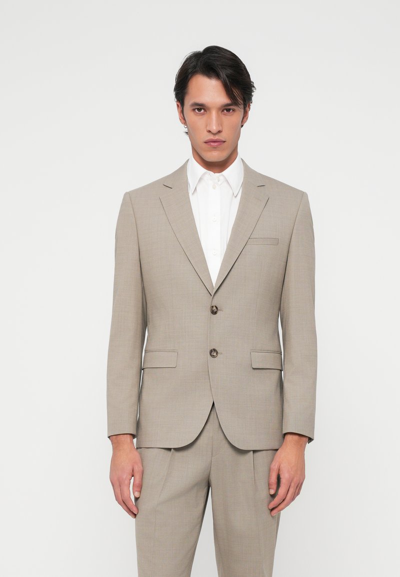 Ανοιχτό μπεζ κοστούμι με υφαντική υφή, μονόχρωμο σχέδιο και δύο κουμπιά. Συνδυάζεται με κλασικό λευκό πουκάμισο. Ραμμένο για τέλεια εφαρμογή.