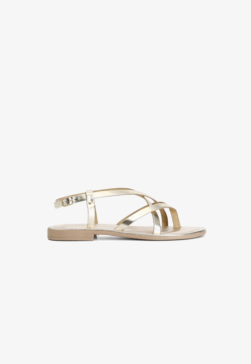 Tasot litteät sandaalit, joissa on metallinhohtoiset kultaiset hihnat, ristikkäinen muotoilu, säädettävä solki ja vaaleanbeige pohja. Minimalistiset ja avonaiset varpaat.