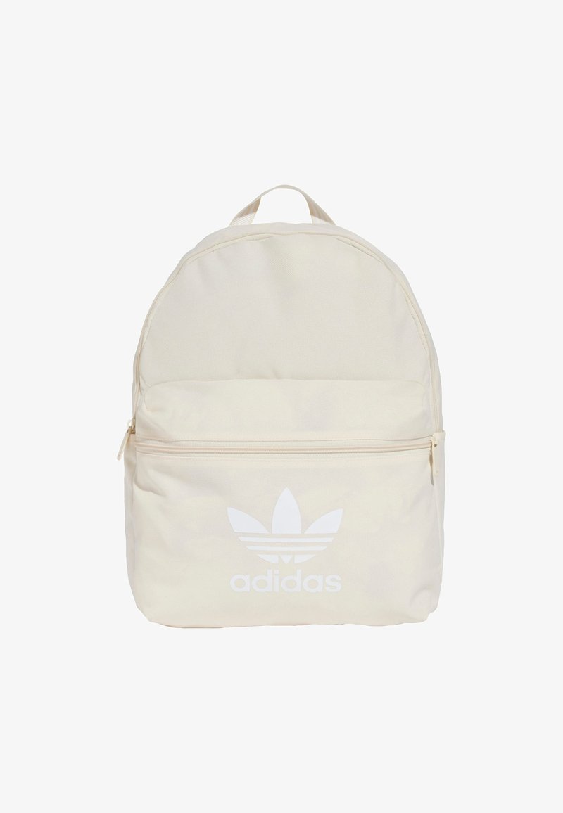 Zaino beige chiaro con cerniera bianca e logo Adidas. Forma rotonda, materiale in tessuto, scomparto unico e tasca frontale.