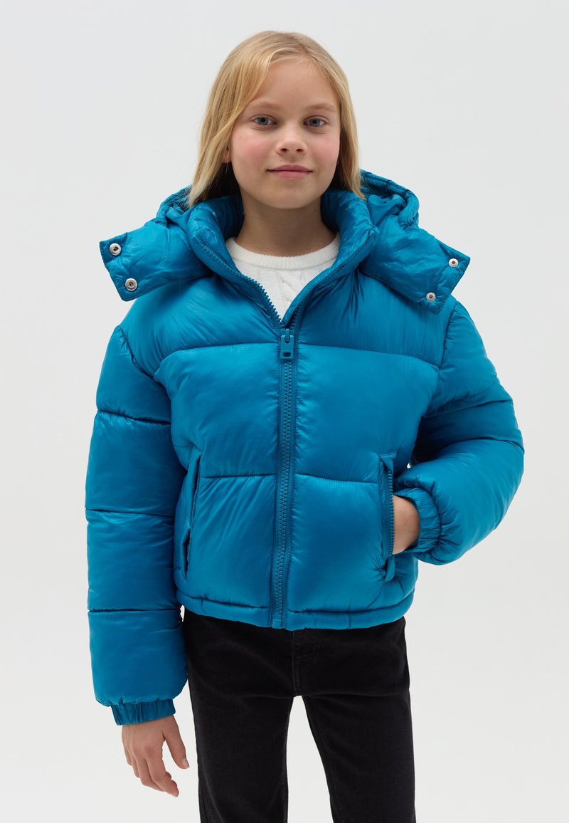 Giacca a vento teal con cappuccio, dotata di zip frontale, polsini elasticizzati e due tasche frontali, realizzata in tessuto lucido e trapuntato.