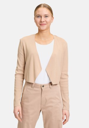 Beige verkürzter Cardigan aus weichem Strickstoff, mit langen Ärmeln und einem schlichten offenen Design, über einem weißen Oberteil getragen.