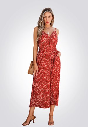 Red floral jumpsuit with spaghetti straps, cinched waist, wide legs, and pockets. Features white small flowers on a textured fabric.