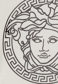 Bílá látka se složitým černým grafickým motivem ženské tváře obklopené dekorativním řeckým klíčovým vzorem.