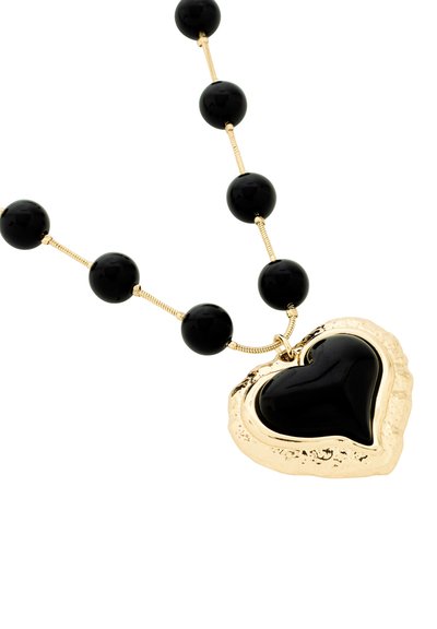 Collier en perles noires présentant un grand pendentif en forme de cœur avec des accents dorés, avec une surface noire lisse et une bordure en or texturée.