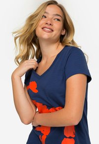 Camiseta de cuello en V color azul marino, hecha de algodón suave, con un atrevido diseño gráfico en color naranja. Cuello corto y corte holgado con una textura suave.