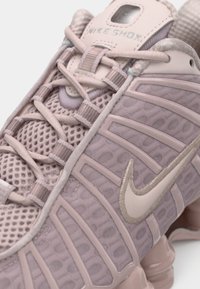 Αθλητικό παπούτσι ανοιχτό ροζ με πλέγμα στο πάνω μέρος, υφασμάτινες λεπτομέρειες και ένα εμφανές λογότυπο Swoosh. Διαθέτει επενδεδυμένο κολάρο και σχεδιασμό με κορδόνια.