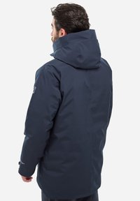 Dunkelblauer wasserdichter Parka mit großer Kapuze, aus glattem, leichtem Material gefertigt. Verfügt über ein dezentes Logo am Ärmel.