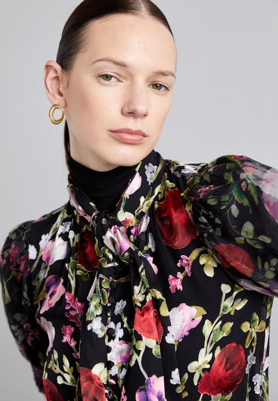 Floral blouse featuring a black background with red, pink, and purple flowers. Soft fabric with puff sleeves and a bow tie neckline.