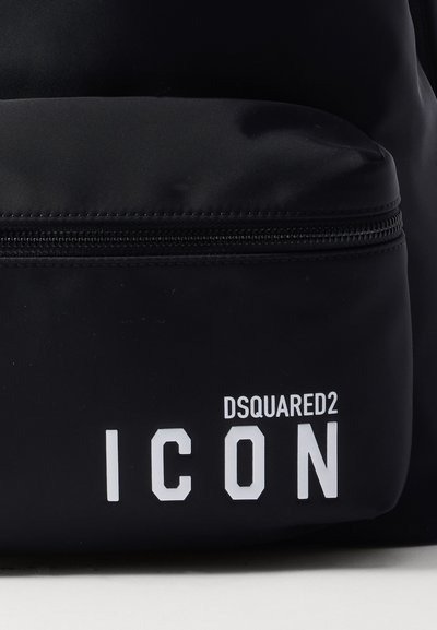 Sac à dos noir en nylon avec une poche zippée à l'avant, logo blanc "DSQUARED2 ICON" et texture lisse. Design minimaliste sans motifs.