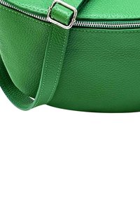 Groene leren schoudertas met een gestructureerde afwerking, ronde vorm, zilveren rits en verstelbare schouderband.