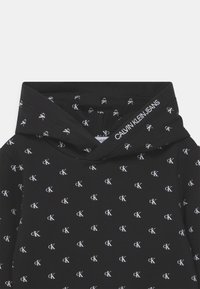 Felpa nera con cappuccio caratterizzata da un motivo ripetuto del logo bianco "CK". Cappuccio con un dettaglio del logo visibile lungo il bordo. Tessuto morbido e strutturato.