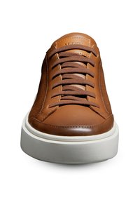 Basket en cuir brun avec texture perforée sur l'ensemble, bout rond, lacets bruns et semelle en caoutchouc blanche. Présente un logo de la marque embossé sur la languette.