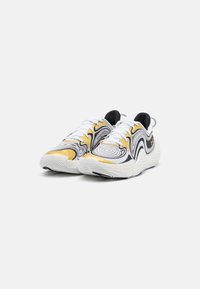 Witte sneakers met een draaikolkje in zwart en goud, een gestructureerde tussenzool en zwarte accenten op de tong en hiel.