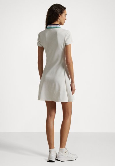 Īsām piedurknēm, gaiši pelēka polo kleita ar izplestu svārku. Ietver daudzkrāsainu caurspīdīgu apkakli un diskrētu logotipu aizmugurē.