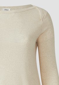 Beige geribde lange mouwen top met een ronde hals en een licht getailleerd ontwerp. Materiaal heeft een zachte textuur met lichte kleurvariaties.
