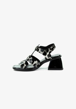 Czarno-białe sandały w wzór panterki z połyskującym wykończeniem, otwarte z przodu, z trzema elastycznymi paskami. Posiadają geometryczny, czarny blokowy obcas.