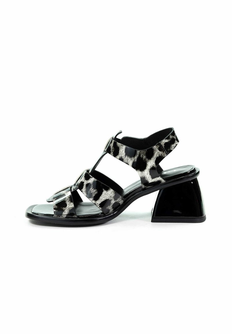 Czarno-białe sandały w wzór panterki z połyskującym wykończeniem, otwarte z przodu, z trzema elastycznymi paskami. Posiadają geometryczny, czarny blokowy obcas.