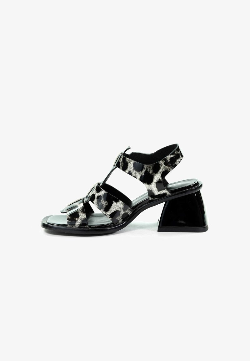 Czarno-białe sandały w wzór panterki z połyskującym wykończeniem, otwarte z przodu, z trzema elastycznymi paskami. Posiadają geometryczny, czarny blokowy obcas.