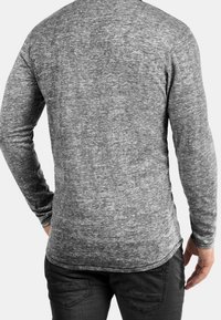 Langärmliges graues T-Shirt mit einer strukturierten, melierten Optik. Verfügt über einen abgerundeten Saum und eng anliegende Ärmel, gefertigt aus weichem, elastischem Stoff.