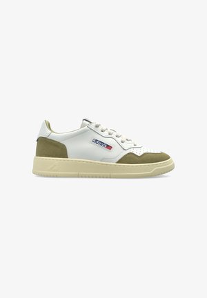 Sneaker bianca low-top con punta e tallone in camoscio beige, dettaglio traforato, chiusura con lacci e una toppa con il logo sul lato.