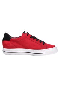 Baskets basses rouges avec languette noire au talon, lacets noirs, semelle blanche avec des rayures noires, vues du côté extérieur.