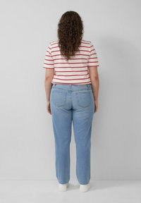 Lichtblauwe rechte jeans met twee achterzakken, gecombineerd met een kortärmegere wit shirt met rode horizontale strepen.