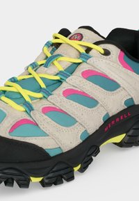 Chaussure de randonnée avec tige beige, bleu sarcelle et rose, lacets jaune vif et semelle noire robuste avec accents jaunes marquée Merrell.