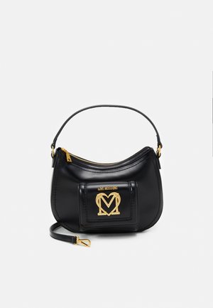Sac à main en cuir noir de forme courbée, doté d'un logo doré et d'une fermeture éclair. Il possède une courte sangle et une finition texturée.