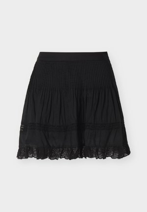 Μαύρη πλισέ φούστα με δαντελωτό τελείωμα κοντά στο ποδόγυρο και φαρδύ ζωνάρι, εμφανιζόμενη πάνω σε απλό ανοιχτό φόντο.