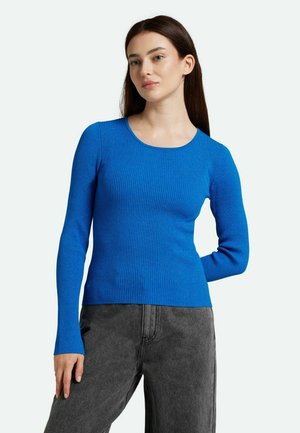 Helles blaues, geripptes Langarmoberteil mit rundem Ausschnitt, ausgestattet mit enganliegenden Ärmeln und einer glatten Textur, kombiniert mit dunkelgrauen, weiten Hosen.