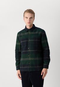 Tumedas rohelises ja tumesinises pliidimustriga flanellist särk, millel on nööpidega esiosa, krae ja kaks rinna-taskut. Pehme tekstuur.