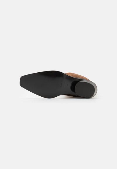 Braunes Leder-Schuh mit einer schlanken, spitzen Zehe, ausgestattet mit einer glatten schwarzen Gummisohle und einem abgerundeten metallischen Absatzakzent.