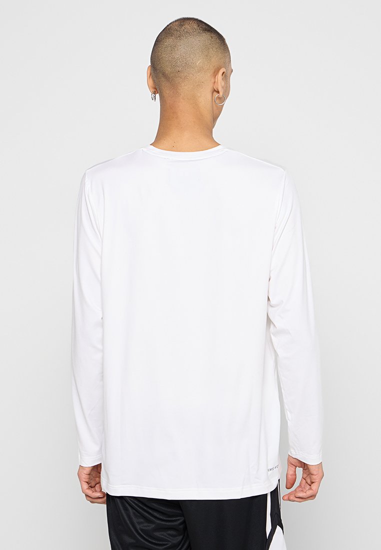Chemise à manches longues en tissu blanc, dotée d'un col rond et d'une texture lisse, avec un ourlet droit et des détails de design minimalistes.